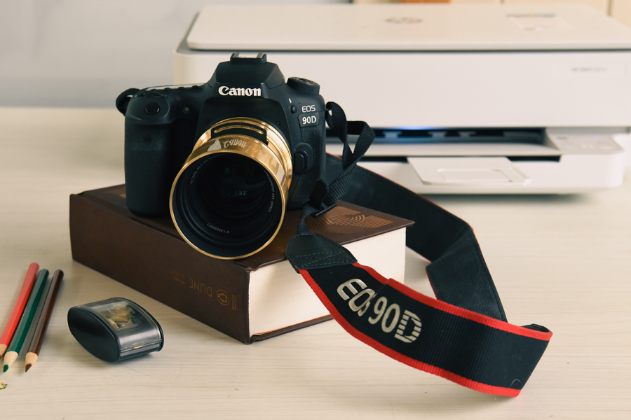 Canon 90D encima de una copia de Dune en un escritorio con una lente Petzval colocada.